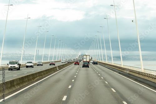 Lisbon, Portugal - October 31, 2024: Traffic on The Vasco da Gama Bridge (Portuguese: Ponte Vasco da Gama) is a cable-stayed bridge in a rainy day. photo