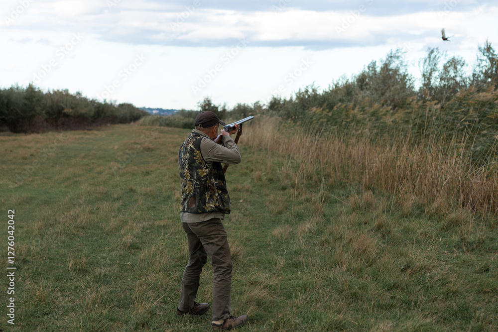 Hunter aiming with rifle while standing against sky Hunter aiming with rifle while standing against sky