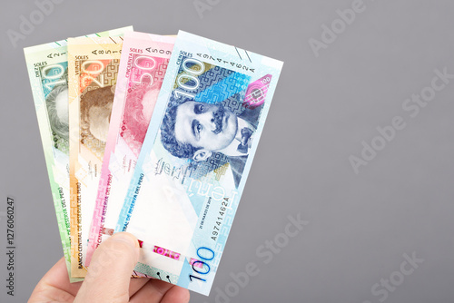 Peruvian money in the hand on a gray background.