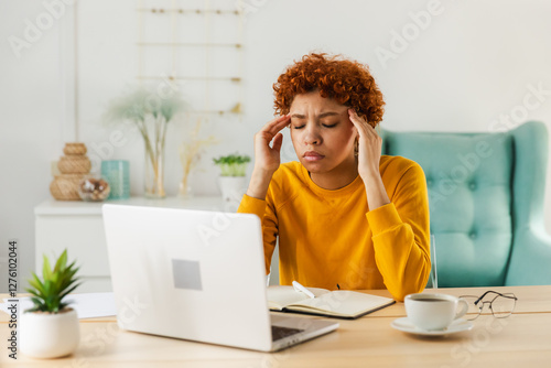 African woman touching temples experiencing stress. Girl at home office tired of working feeling headache sick rubbing temples forehead. Long laptop usage computer vision syndrome. Office syndrome photo