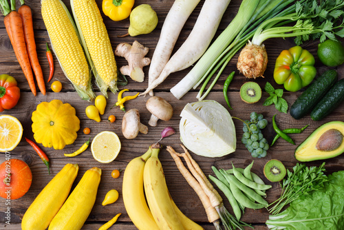 White, green, yellow, orange fruits and vegetables on wooden background.  Healthy food. Multicolored raw food.