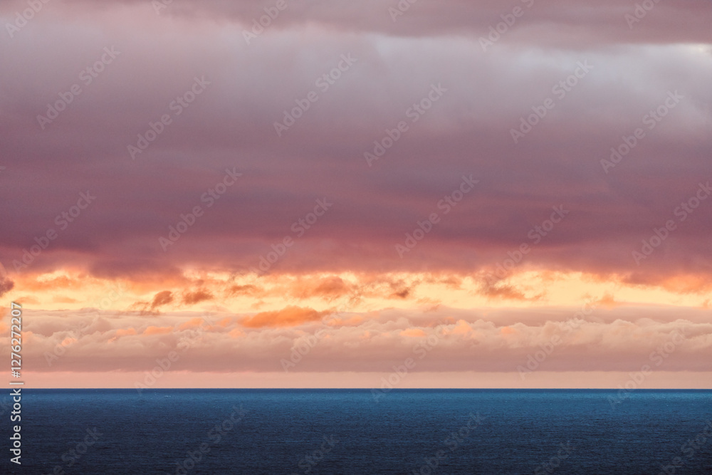 A stunning ocean view at sunset with vibrant orange and pink clouds contrasting against the calm blue water and dramatic sky A stunning ocean view at sunset with vibrant orange and pink clouds contrasting against the calm blue water and dramatic sky