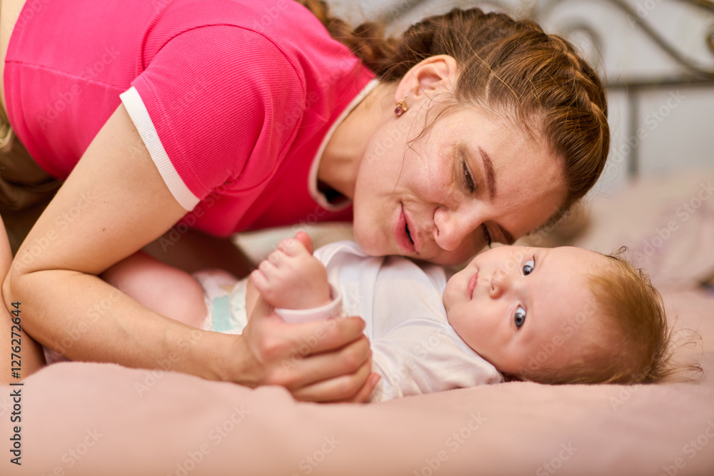 Young caucasian mother with braided brown hair cherishes infant girl. Lying on soft bed in gentle lighting, showing affectionate bond and nurturing presence Young caucasian mother with braided brown hair cherishes infant girl. Lying on soft bed in gentle lighting, showing affectionate bond and nurturing presence