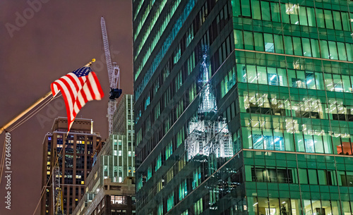Night view of American flag reflecting on a building in New York City