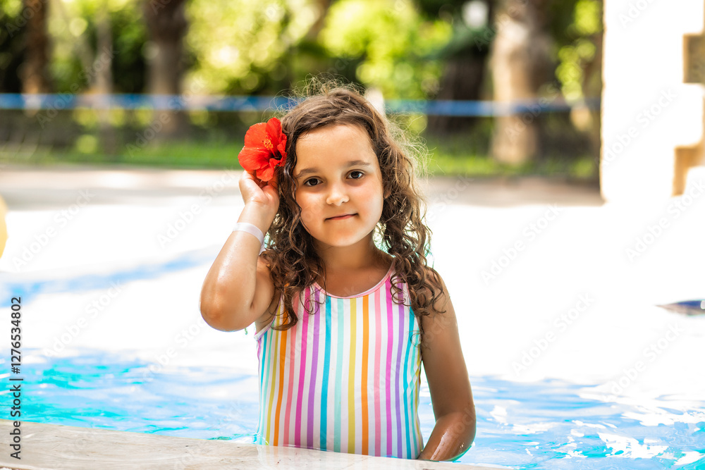 Naklejka premium Happy kid little girl playing in outdoor swimming pool at sunny day. Active vacation and healthy lifestyle. Happy summertime.