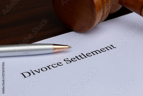Fotografía A divorce settlement paper placed beside a gavel and pen on a warm wooden surface, symbolizing legal finalization