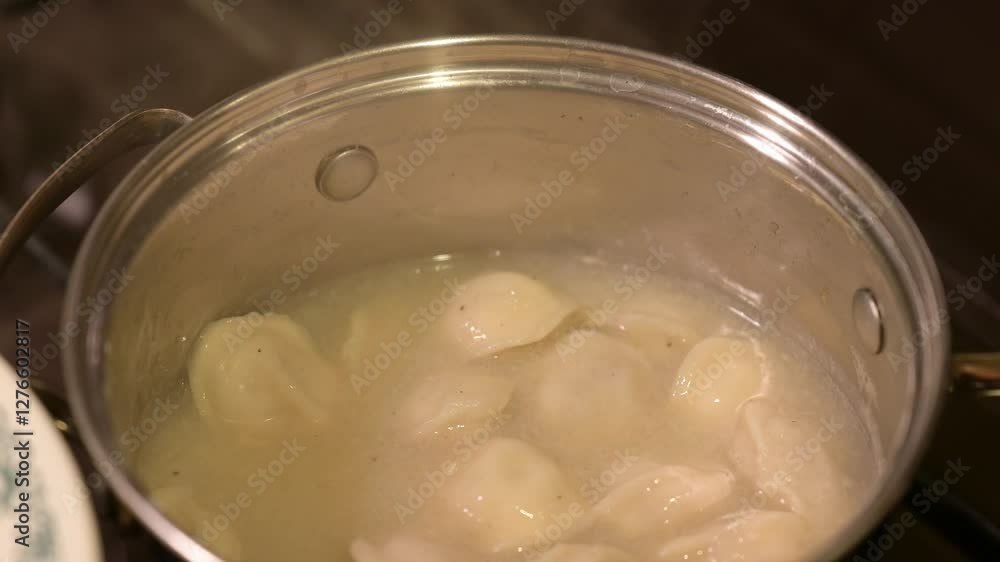 Cooking dumplings at home. Taking ready just cooked boiled dumplings from the deep metal pot Cooking dumplings at home. Taking ready just cooked boiled dumplings from the deep metal pot