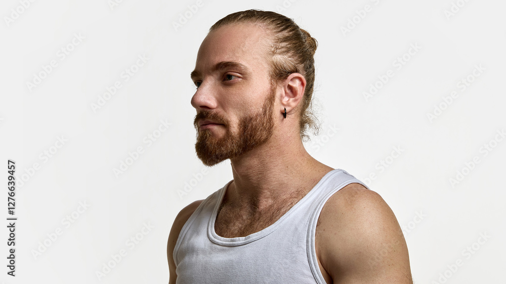 Man with tied-back hair and beard in white tank top, looking straight, showcasing masculine elegance against white studio background. Concept of male beauty, skin care, health, wellness Man with tied-back hair and beard in white tank top, looking straight, showcasing masculine elegance against white studio background. Concept of male beauty, skin care, health, wellness