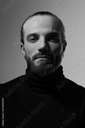 Monochrome portrait of handsome man exuding charisma and strength, highlighting masculine elegance and well-defined facial structure against white studio background. Concept of male beauty, skin care