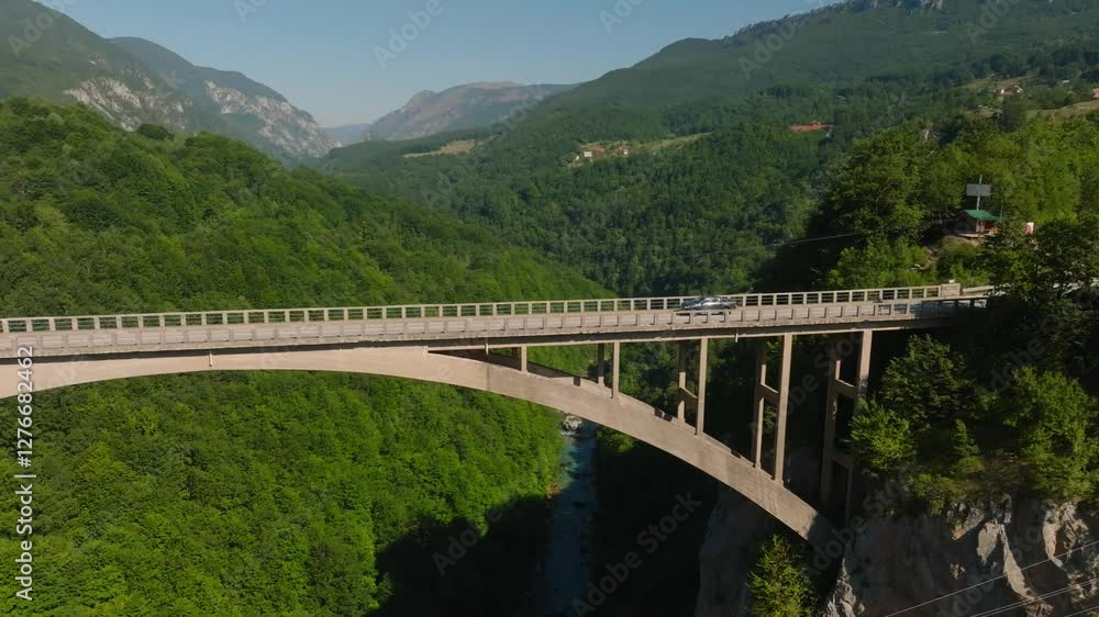 Aerial drone view of a moving pickup truck on the high concrete Djurdjevic Bridge over the Tara River Canyon with mountains in the background, Montenegro, Europe Aerial drone view of a moving pickup truck on the high concrete Djurdjevic Bridge over the Tara River Canyon with mountains in the background, Montenegro, Europe