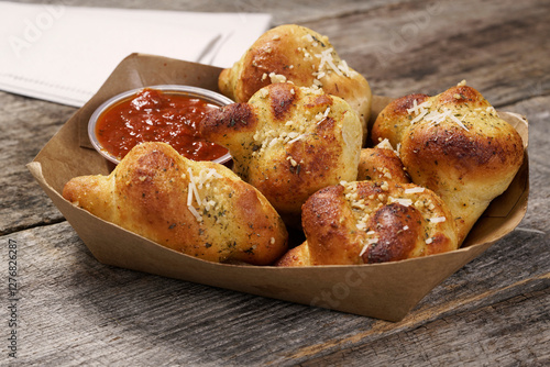 Italian garlic bread knots with marinara dipping sauce in food basket on rustic wood surface