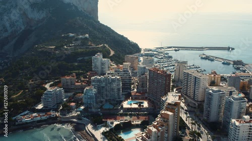 Aerial view to Calpe cityscape. Penyal dIfac Natural Park, harbour with nautical vessels and modern skyscraper coastal buildings surrounded by Mediterranean Sea waters, panorama. Costa Blanca. Spain