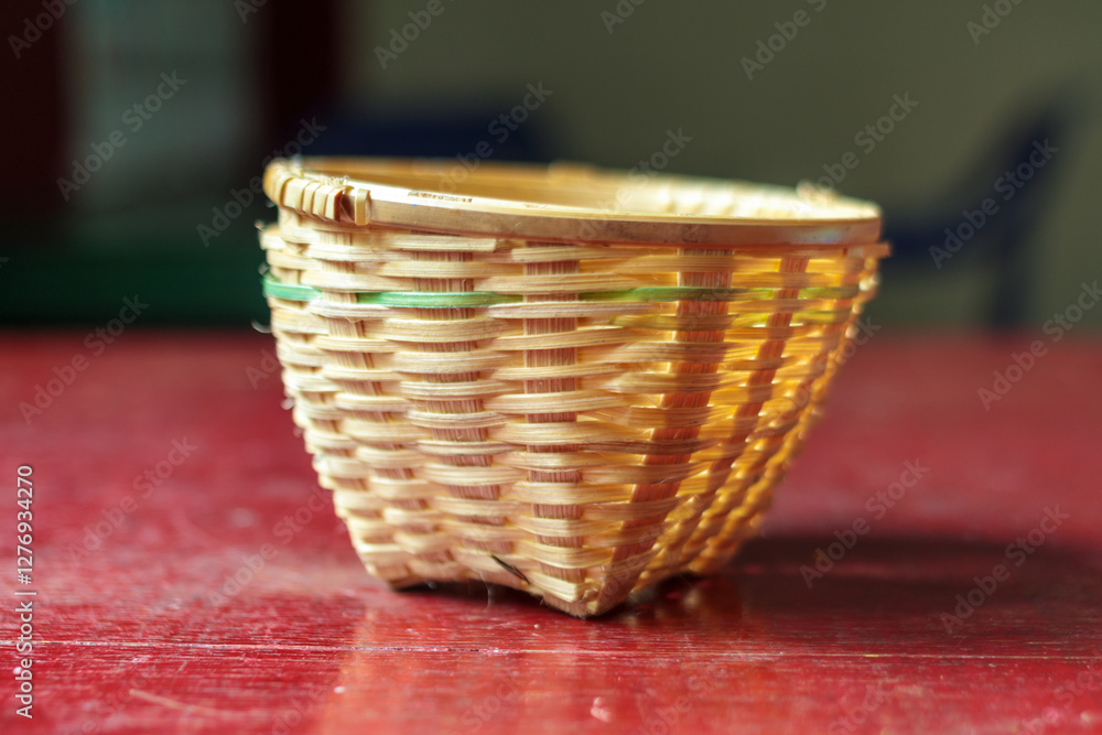 Fototapeta premium Handwoven Bamboo Basket on a Rustic Red Table