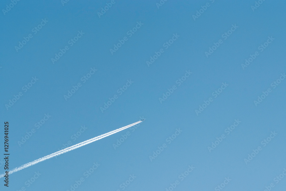 airplane in flight and white stripe against blue sky airplane in flight and white stripe against blue sky