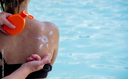 Woman applying sunscreen on child's back. Sun protection. photo