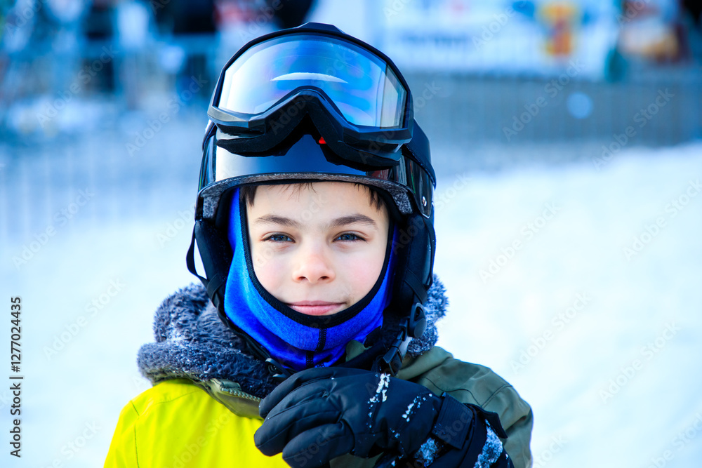 Portrait of little boy in ski equipment at ski resort