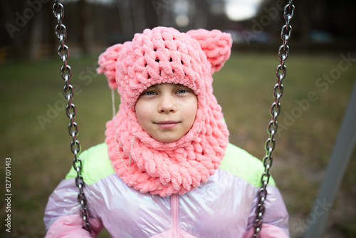Obraz na płótnie Little funny girl in funny pink hat swinging on swing in park outdoors w salonie