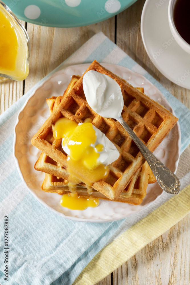 Belgian waffles with cream and lemon curd, served with tea.