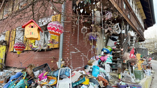 Bild auf Leinwand A unique and chaotic scene of a house exterior filled with hanging decorations, colorful hot air balloon ornaments, and a wooden birdhouse attached to a tree