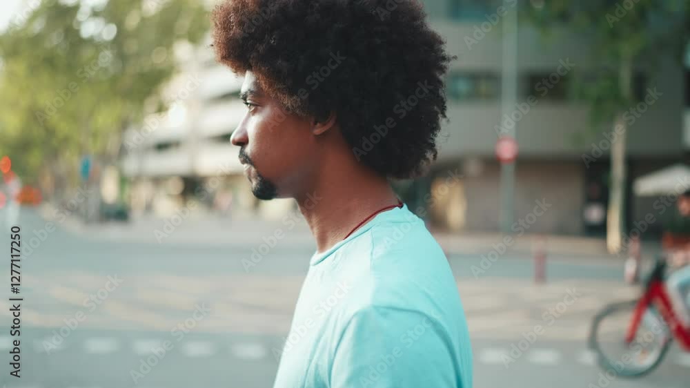 Closeup of young African American man in light blue t-shirt crossing the road at crosswalk. lifestyle concept. slow motion Closeup of young African American man in light blue t-shirt crossing the road at crosswalk. lifestyle concept. slow motion