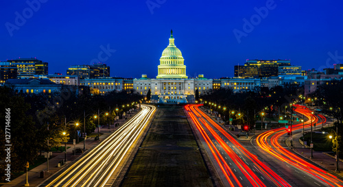 A blurred motion shot of car lights streaking through the streets, with the Washington D.C. Capitol building glowing in the background, creating a dynamic and atmospheric cityscape.