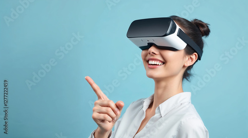 woman in virtual reality glasses pointing at smth and smiling, light blue background photo