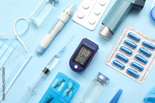 Composition with pulse oximeter, inhaler, syringe and medicines on blue background photo