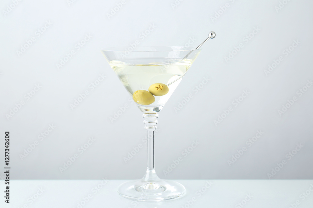 Martini cocktail with olives in glass on light grey table Martini cocktail with olives in glass on light grey table