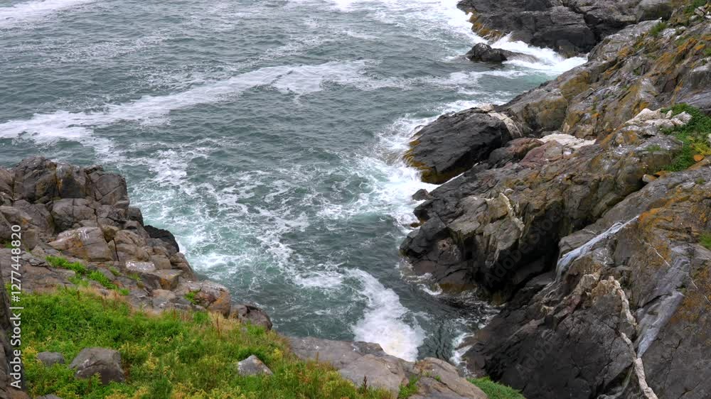 A high angle view of the ocean waves on the rocky shore along the coast of Monhegan Island, Maine on a foggy day. A high angle view of the ocean waves on the rocky shore along the coast of Monhegan Island, Maine on a foggy day.
