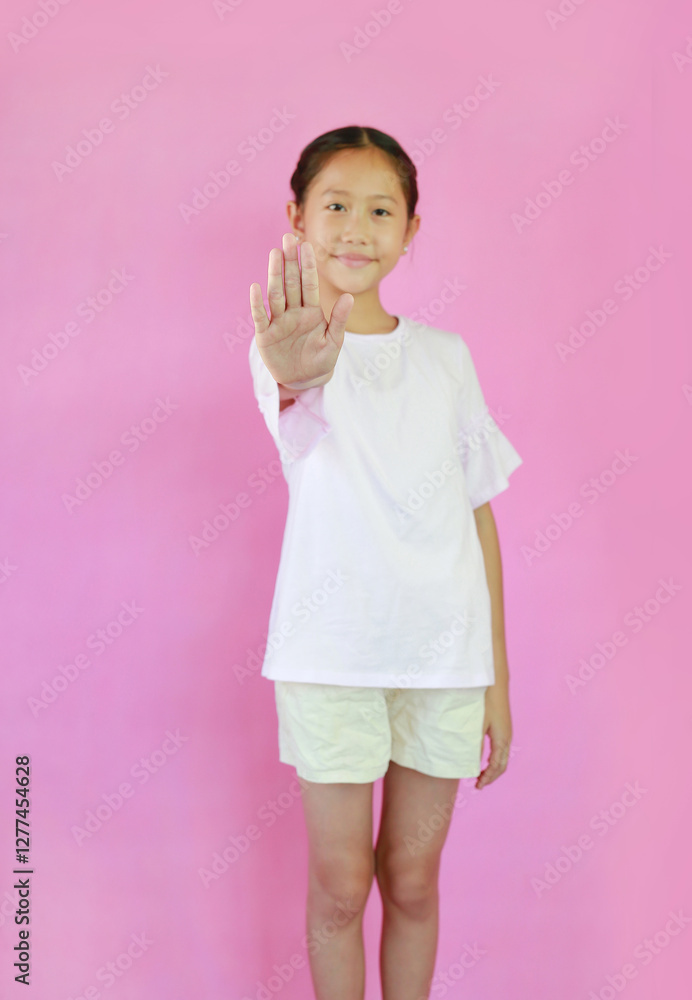 Soft-focus Asian girl child show stop sign gesture isolated on pink studio background. Focus at palm. Soft-focus Asian girl child show stop sign gesture isolated on pink studio background. Focus at palm.