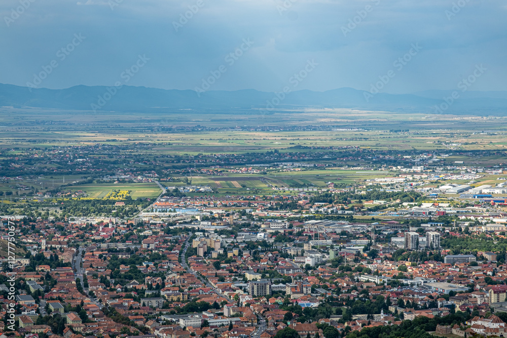 Fototapeta premium Aerial view of Brasov surrounded by the Carpathian mountains dotted with ski resorts including the ever popular Boiana Brasov. Romania, the Balkans, Eastern Europe
