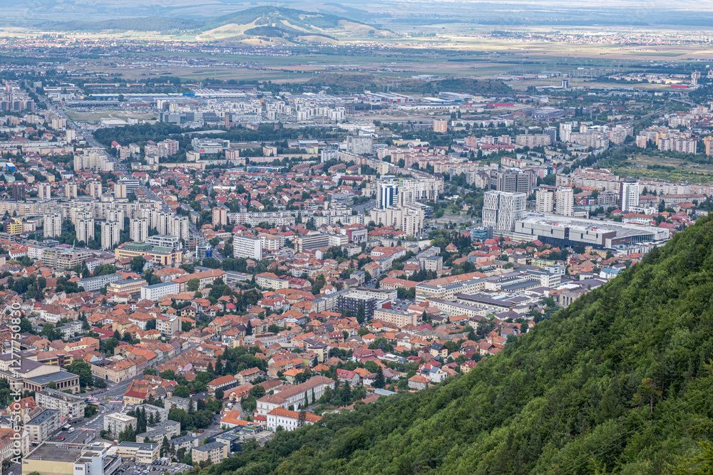 Fototapeta premium Aerial view of Brasov surrounded by the Carpathian mountains dotted with ski resorts including the ever popular Boiana Brasov. Romania, the Balkans, Eastern Europe