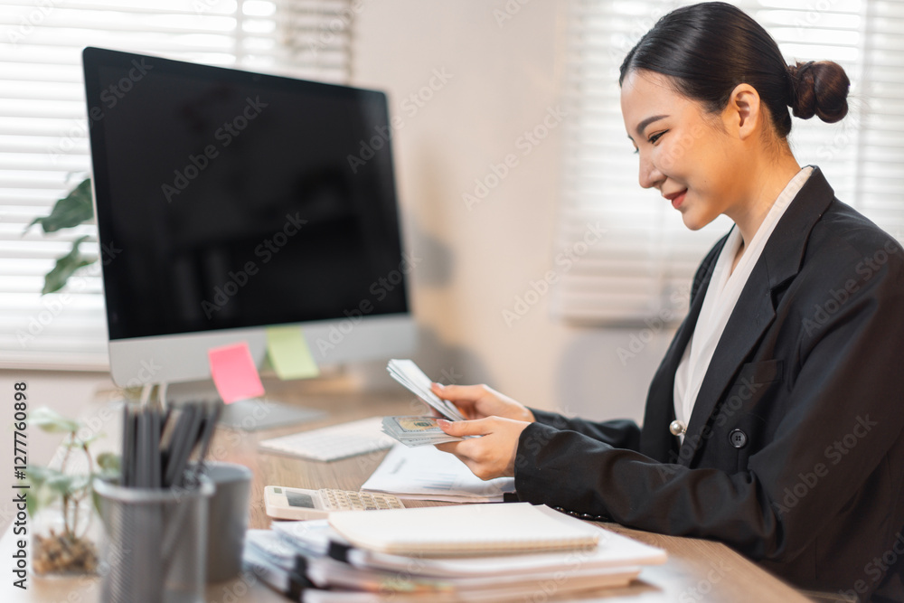 Young committed asian business the data analyst woman counts money in hands sitting with a desktop computer in the office.
Young committed asian business the data analyst woman counts money in hands sitting with a desktop computer in the office.