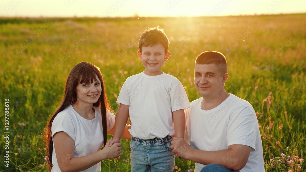 Family of three on picnic in meadow in flowers, summer park. Family has fun, smiles, plays together. Mother father, son play in spring park. Child mom dad are resting on lawn. Family weekend in nature Family of three on picnic in meadow in flowers, summer park. Family has fun, smiles, plays together. Mother father, son play in spring park. Child mom dad are resting on lawn. Family weekend in nature