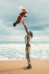 Happy family father and child playing at the beach. Dad throws daughter into  the air, kid girl traveling with parent summer vacations outdoor love and joy bonding candid emotions