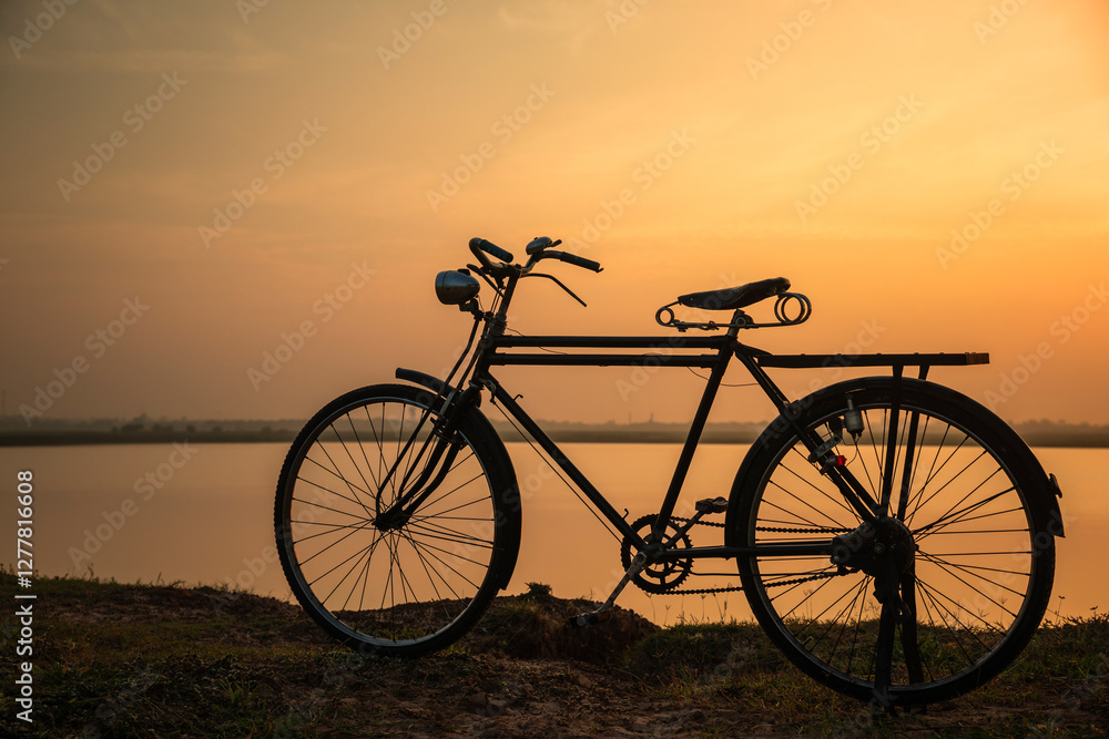 Silhouete of old rusty retro style bicycle during sunrise with golden sky background. Silhouete of old rusty retro style bicycle during sunrise with golden sky background.