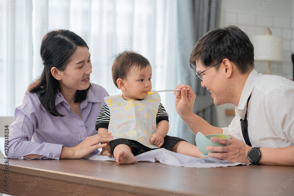 Family enjoys mealtime together while teaching baby to eat independently at home Family enjoys mealtime together while teaching baby to eat independently at home