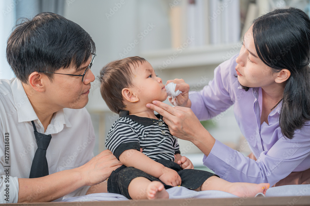 Parents caring for their baby while cleaning his face in a cozy home setting during the afternoon Parents caring for their baby while cleaning his face in a cozy home setting during the afternoon