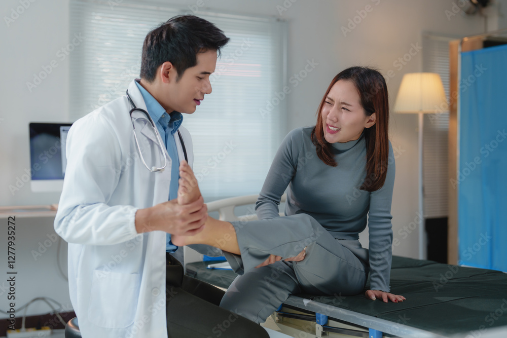 Obraz premium Asian female patient experiencing pain while doctor examining and gently massaging injured ankle during medical consultation in a hospital room, focusing on treatment and care