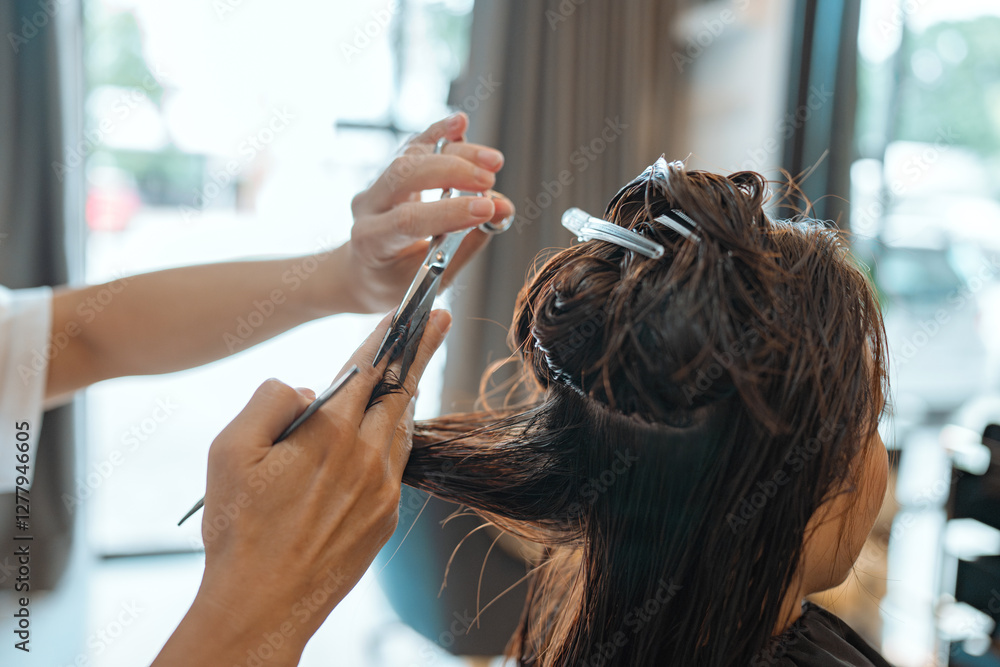 Fototapeta premium Hands of Hairdresser trimming black hair with scissors at hair beauty salon