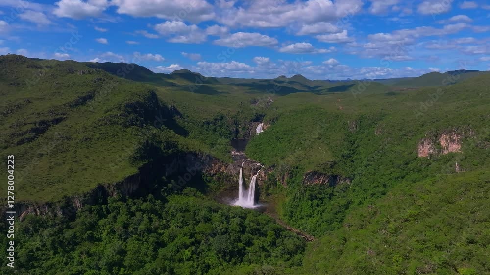 Aerial view of a stunning waterfall cascading down rocky cliffs amidst lush green vegetation in Chapada Dos Veadeiros National Park, Goias, Brazil, showcasing the raw beauty of nature, reveal shot Aerial view of a stunning waterfall cascading down rocky cliffs amidst lush green vegetation in Chapada Dos Veadeiros National Park, Goias, Brazil, showcasing the raw beauty of nature, reveal shot
