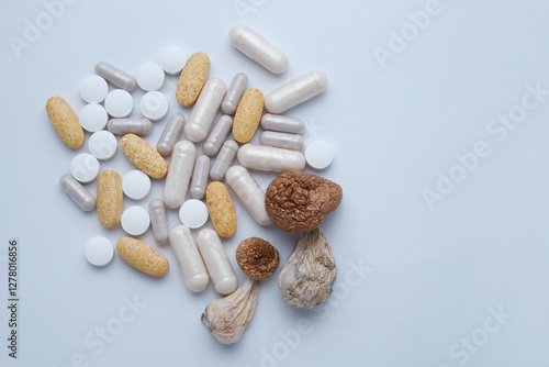 Alternative medicine supplements and dietary drugs for microdosing. Psilocybe Cubensis mushrooms on white studio background, close up. Psilocybin shrooms Golden Teacher with pills, medical capsules