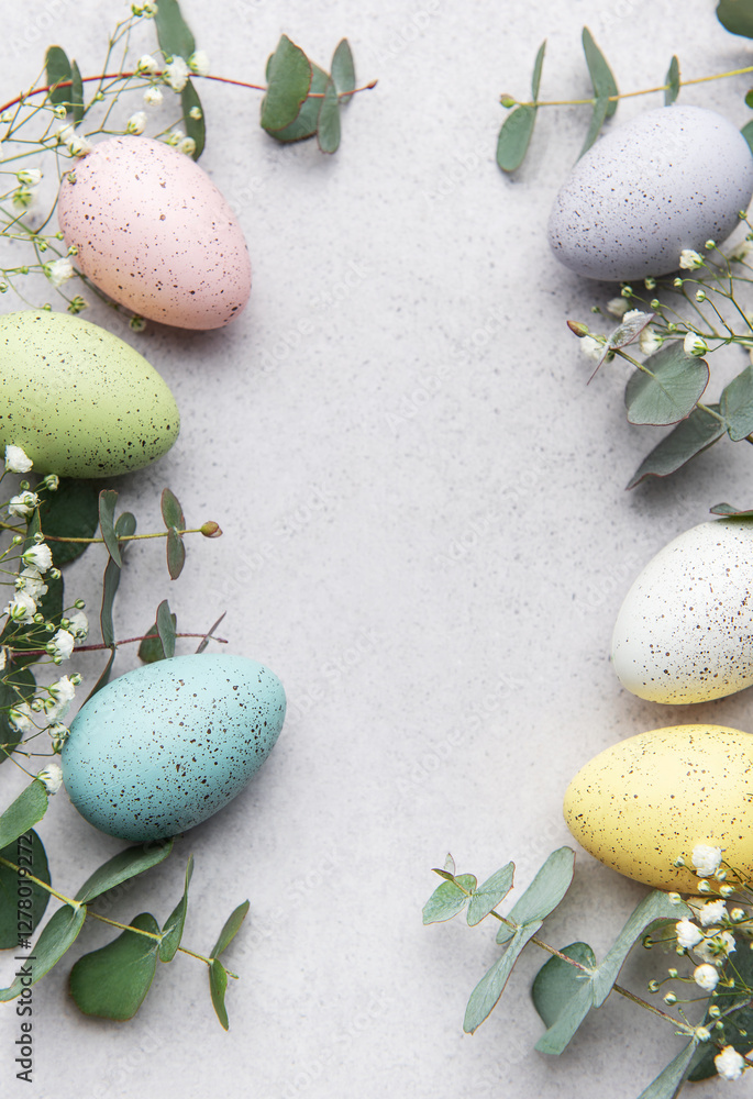 Easter eggs and eucalyptus leaves forming a frame on gray background