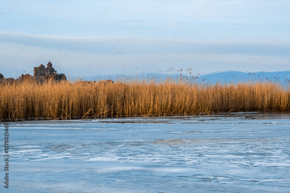 Monastery on the lake shore. Churches on the river bank. Winter landscape with church and lake. Monastery in nature. Frozen lake and rocky mountains Monastery on the lake shore. Churches on the river bank. Winter landscape with church and lake. Monastery in nature. Frozen lake and rocky mountains