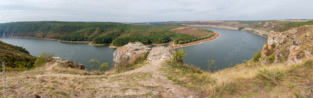 Obraz premium Steep riverbank with limestone rock outcrops at autumn overcast day