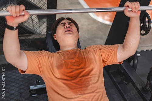 Fat man exhausted from overweight exercise in gym struggling to lift weights photo