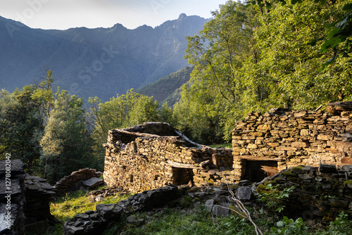Tableau sur toile An old ruined building in Valle Cannobina near Cannobio, in Piedmont, Italy, beutifully lit by the low evening sun, surrounded by lush greenery and mountain views