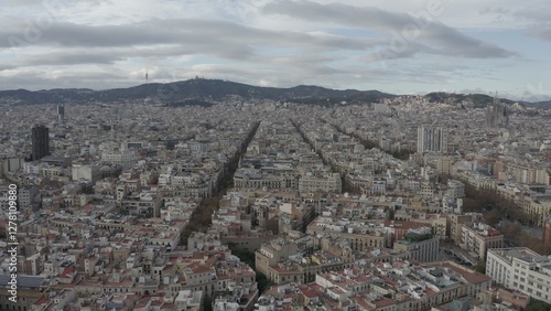 A bird's-eye view of a huge European city with dense multi-storey buildings at the foot of the hill. Sights and residential areas of Barcelona from a drone
