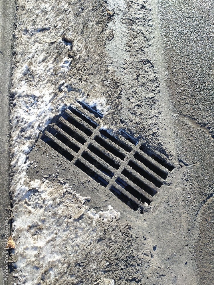 Drainage hatch on the road in winter, closeup of photo