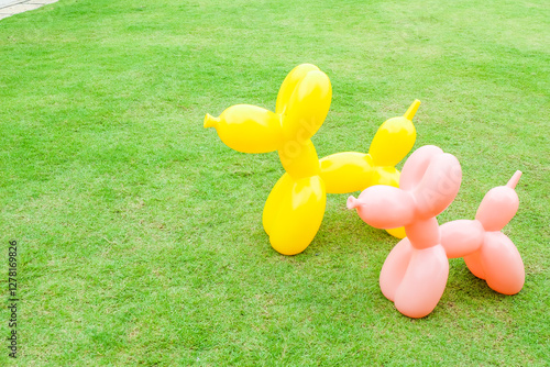 Photography Pink and Yellow Balloon Dog on green grass or park,Background for banner,cute dog toy decor in backyard,backdrop or texture,summer vacation rest in holiday,space for text